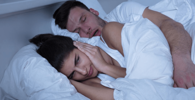 Couple sleeping, lady covering her ears